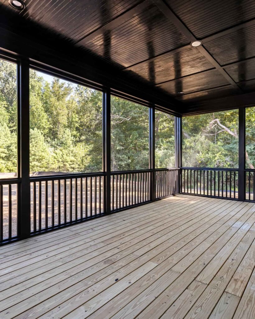 Newly built screened-in porch with dark wood ceiling, sturdy railing, and fresh deck flooring, showcasing Alcord Construction’s detailed outdoor living and porch construction work in Middle Georgia.
