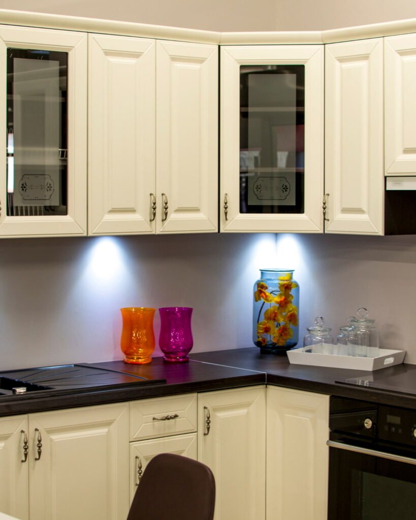 Updated kitchen with cream-colored cabinets, dark countertops, under-cabinet lighting, and modern finishes, showcasing Alcord Construction’s detailed cabinet installation and kitchen remodeling work in Middle Georgia.