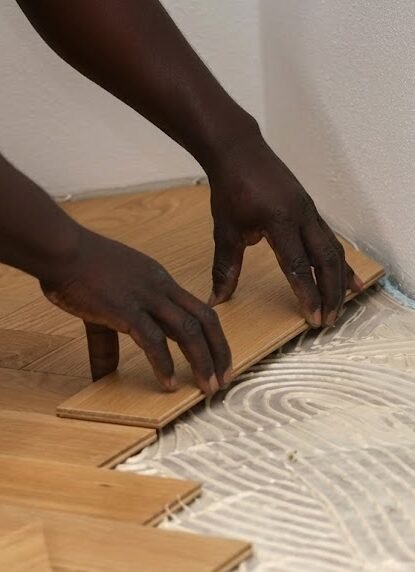 Close-up of hardwood planks being professionally set into adhesive, showcasing Alcord Construction’s skilled, detailed flooring installation work in Middle Georgia.
